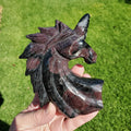 May include: A carved unicorn head sculpture made from black and red banded obsidian. The unicorn has a single horn and a detailed mane.