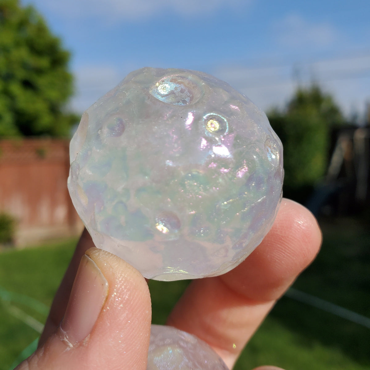 May include: A clear iridescent glass sphere with a textured surface and small air bubbles trapped inside.